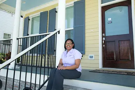 A woman sits on the steps of the entrance to a home