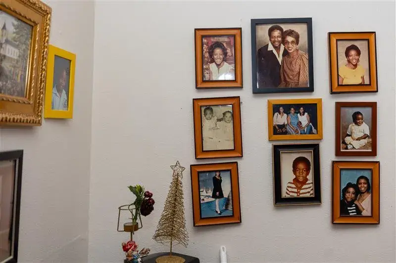 Framed pictures of different family members of Emelda Paul adorn a wall