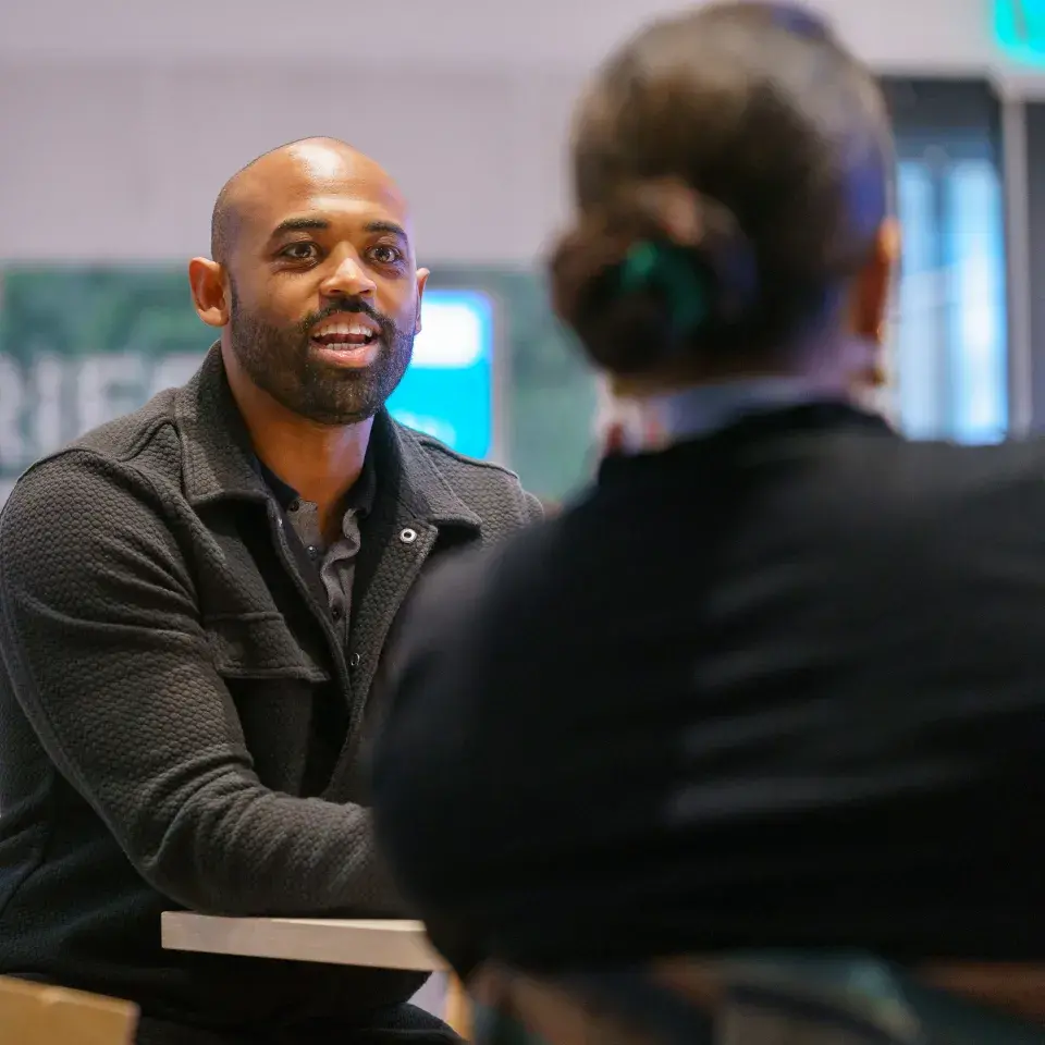 Person smiles, sitting across from another person 