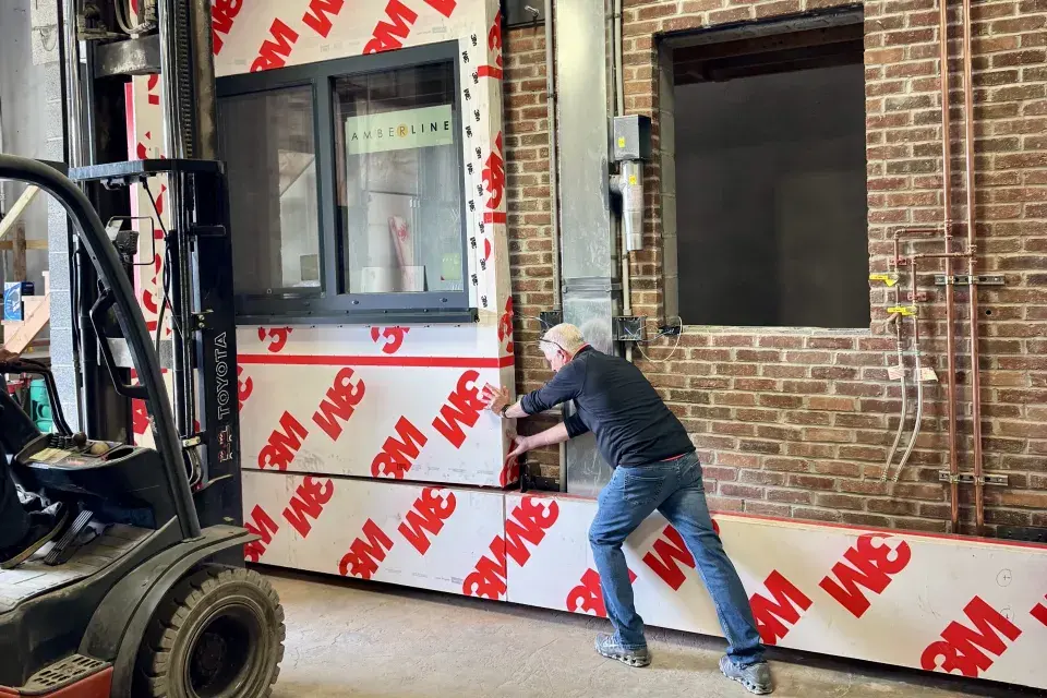 Person installs a prototype of an exterior HVAC panel onto a brick structure