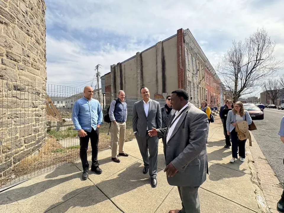 Group of people wearing jackets and dress shirts stand in front a vacant property 