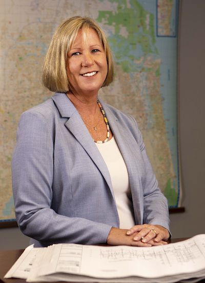 Woman in blue jacket standing in front of housing blueprints