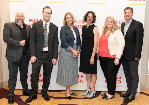 Group of people in business attire standing in front of Wells Fargo backdrop