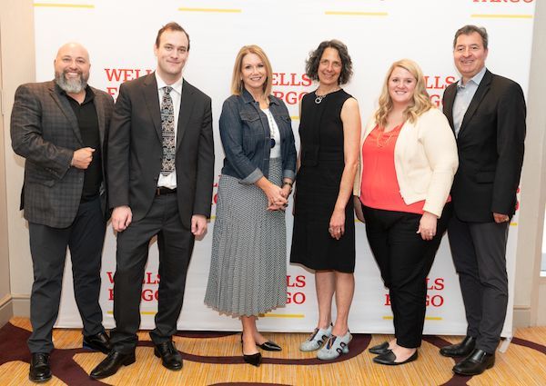 Group of people in business attire standing in front of Wells Fargo backdrop