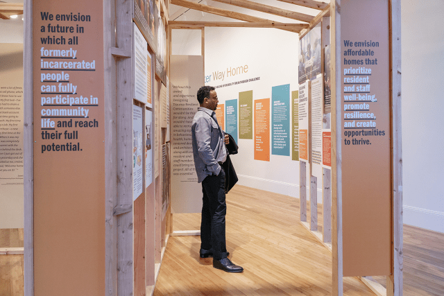 A man standing in between the walls of an exhibit reading the content