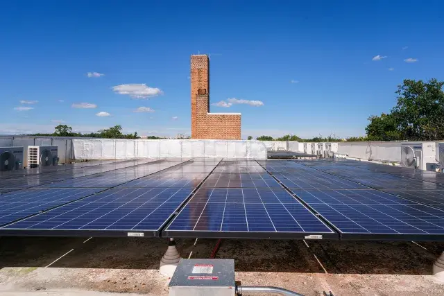 Solar panels with brick tower and blue sky in the background