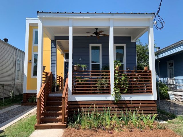 Tidy yellow and blue house with porch and small garden in front