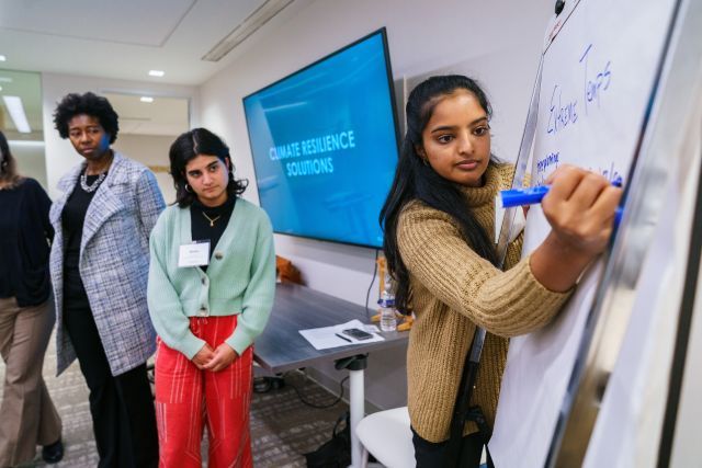 Person writes on a flip chart with people standing near by