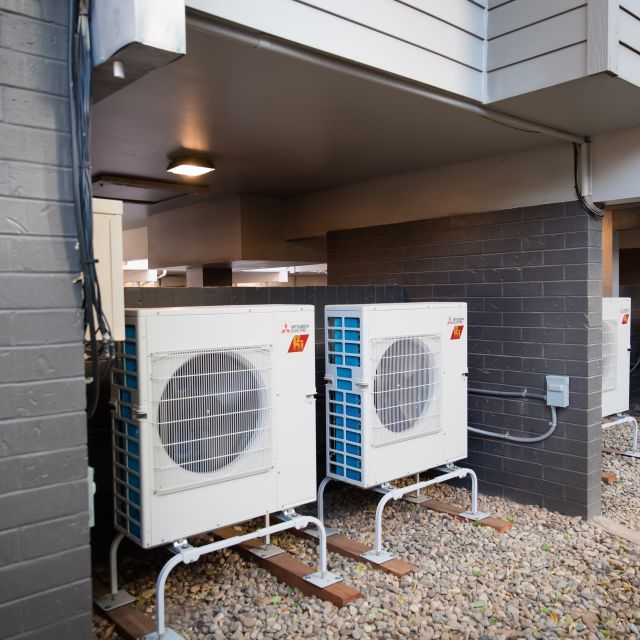 A pair of outside condensers for heat pumps that look like a square with a large circle in the middle