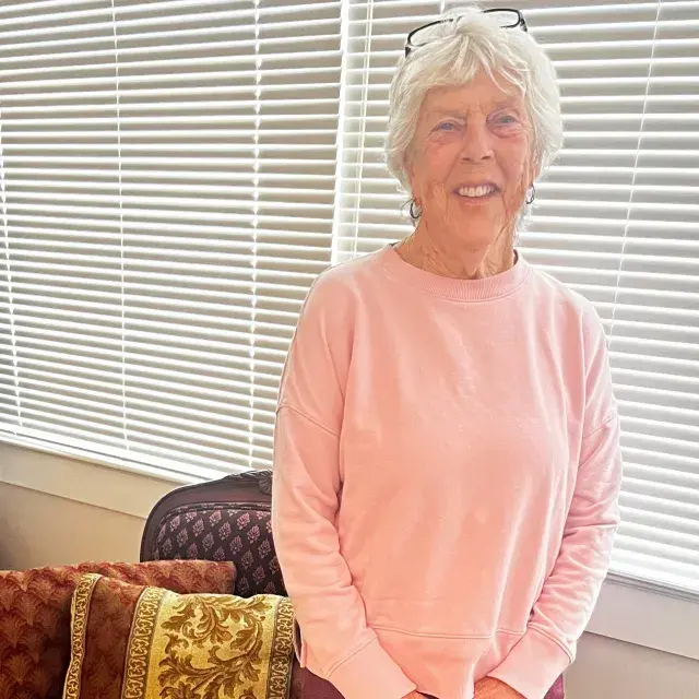 Person smiling short gray hair wearing a pink sweatshirt