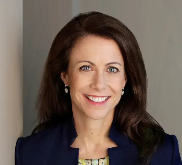 Person with long dark hair smiling and wearing a dark jacket