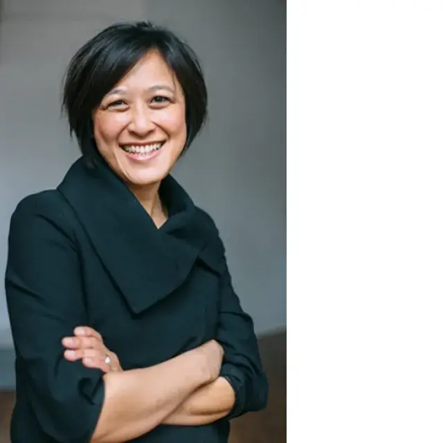 Woman smiles and stands with arms crossed