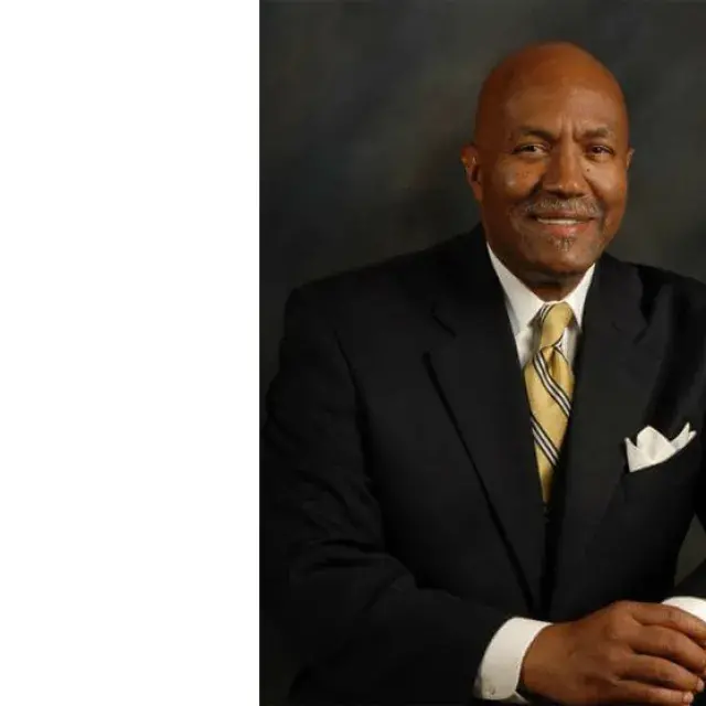 Man seated with hands on top of each other at a table