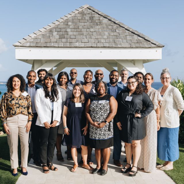 A group of people stand in front of a gazebo overlooking the ocean