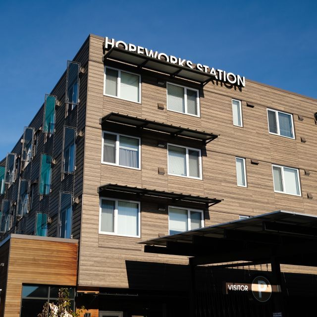 Exterior of multistory brick building with a sign reading "HOPEWORKS STATION" at the top.