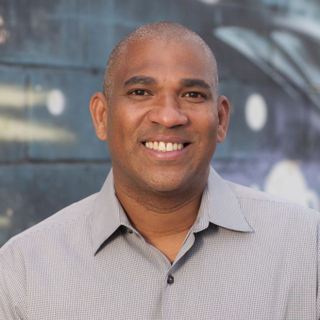 Person smiling and standing in front of blue background