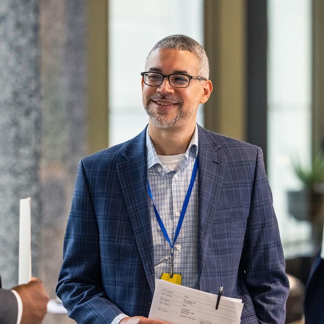 A person standing smiling and holding papers