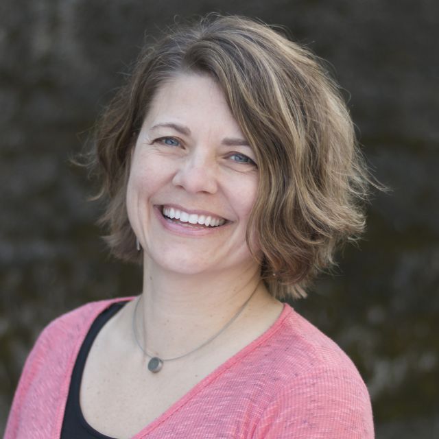 Person smiling with short brown hair, wearing a pink top