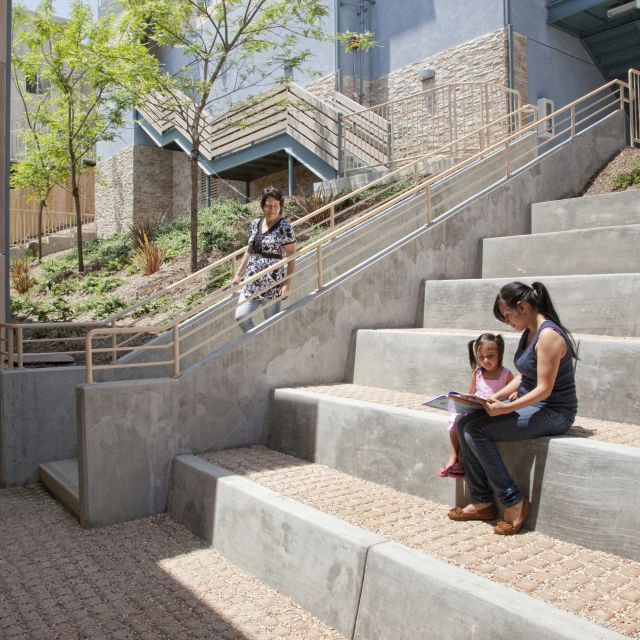 Mother and child sit reading on the stairs of a housing development