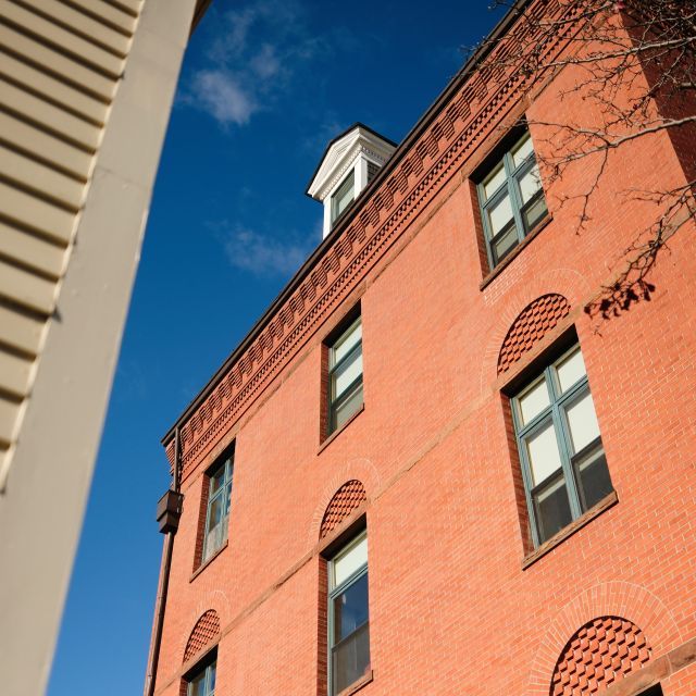 Exterior of red-brick building adjacent to tall sandstone building