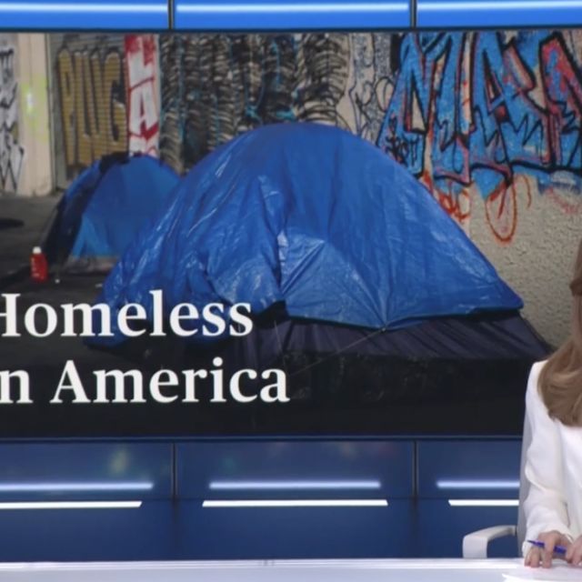 Woman in white jacket in front of Homeless in America backdrop