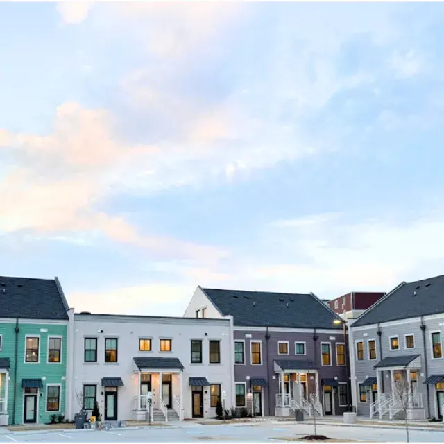 row of multicolored townhomes with a light blue sky with pinkish clouds overhead