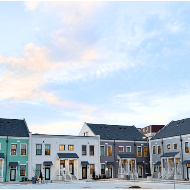 row of multicolored townhomes with a light blue sky with pinkish clouds overhead
