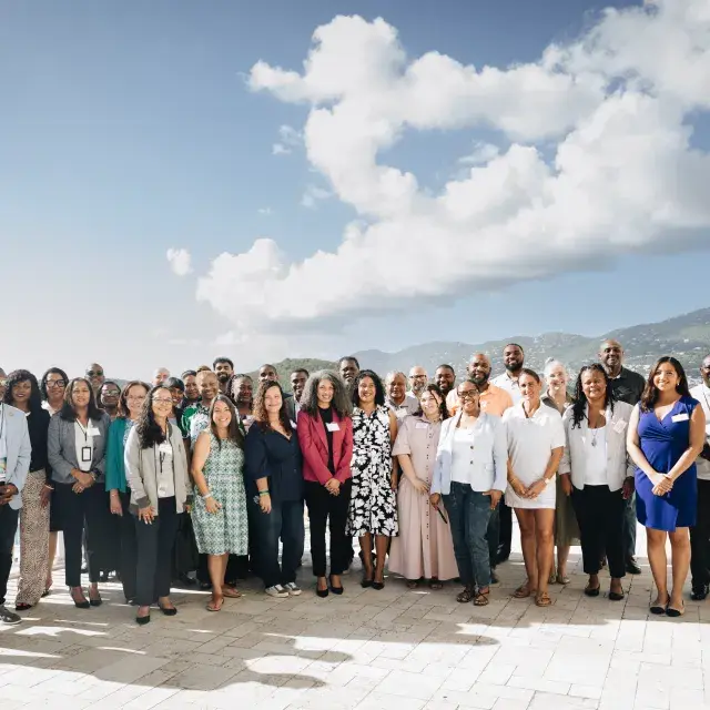 Enterprise U.S. Caribbean team and U.S. Virgin Islands Housing Ecosystem Development Grant Program grantees outside with the ocean and hillside in the background