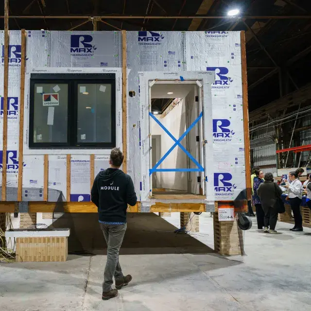 A man inspects a home under construction with people in the background
