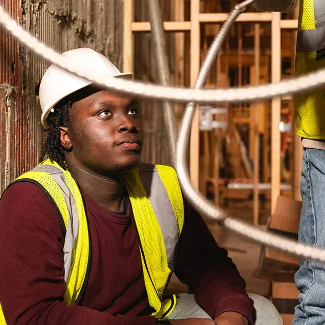 A construction worker wearing a hard hat and looking up