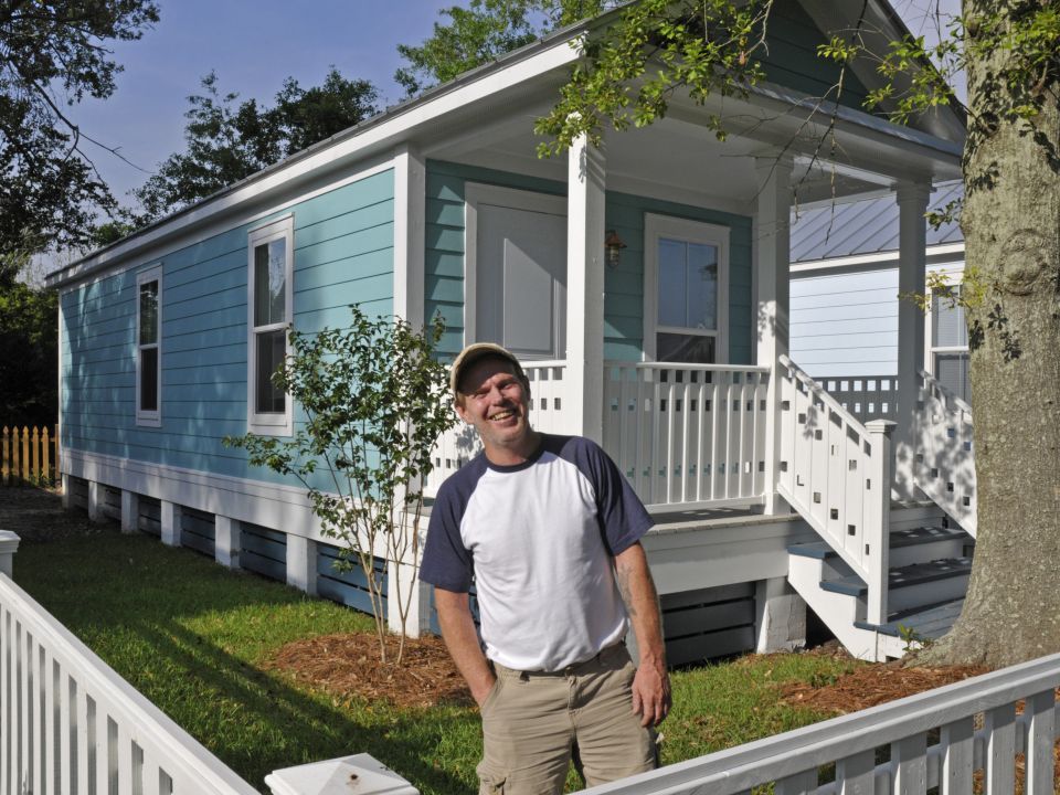 happy man standing in front of a new home