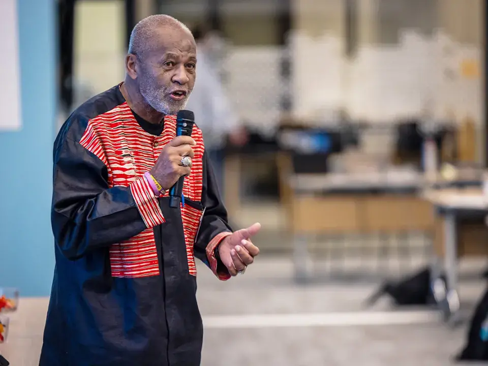 A man wearing red and black speaking into a microphone