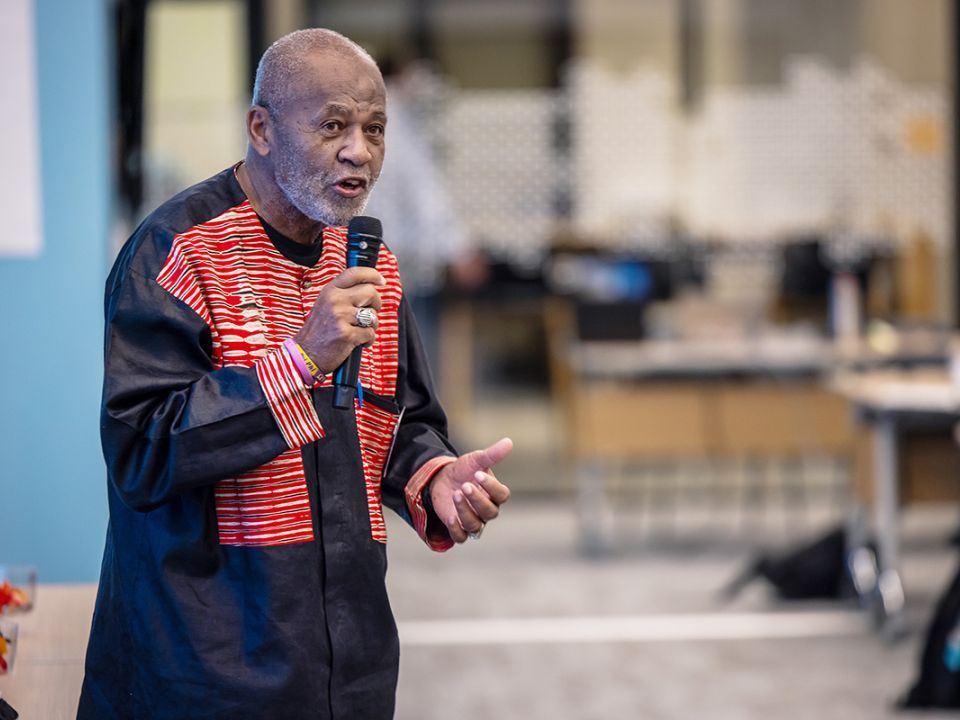 A man wearing red and black speaking into a microphone