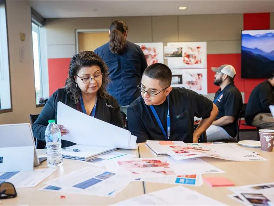 A woman and young man work together reviewing paperwork at a desk