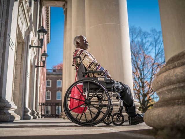 mature man in a wheelchair on front porch of a building