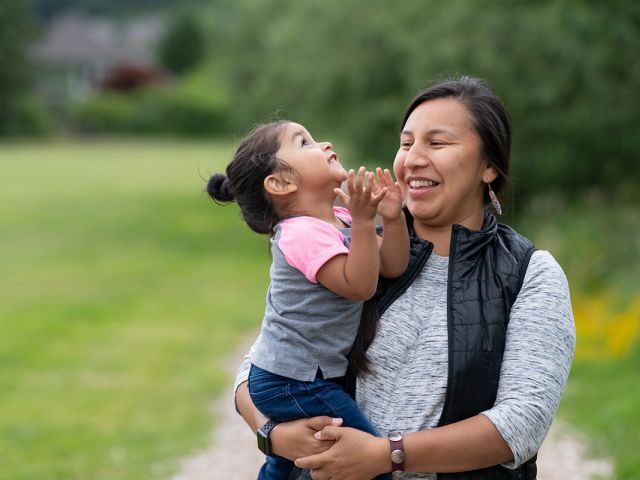 A mother holding her little girl in her arms as they both smile.