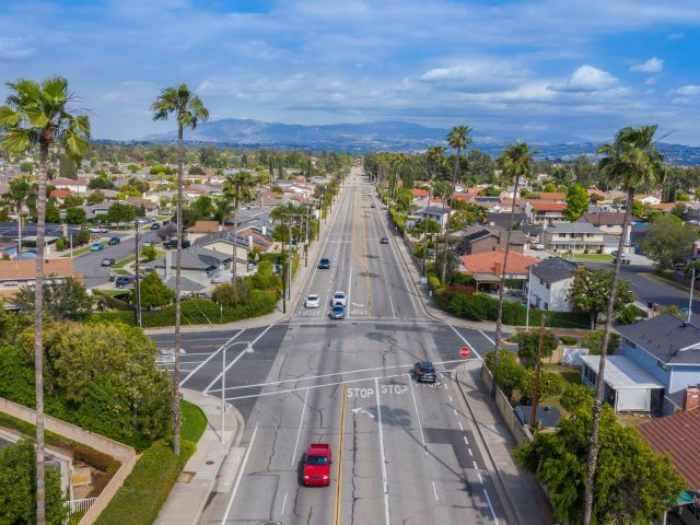 Aerial view of a busy intersection in California with palm trees, buildings, and hills in view