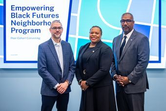 The people in blue, black and gray suites standing in front of a screen