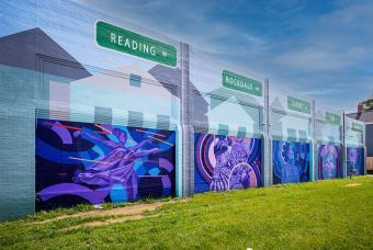 A blue, purple mural wall with street signs.