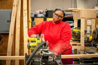 A student in a red shirt using a table saw